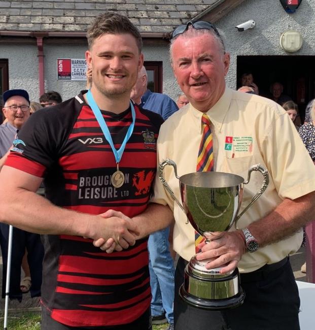 Tenby captain Luke Dedman receives the coveted silverware from sponsor Huw Hughes